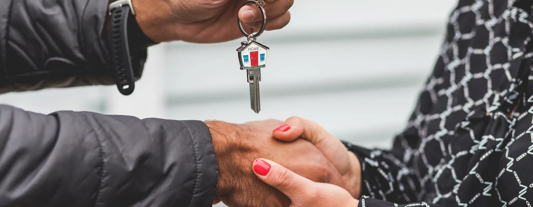 A person handing over a house key to another person.