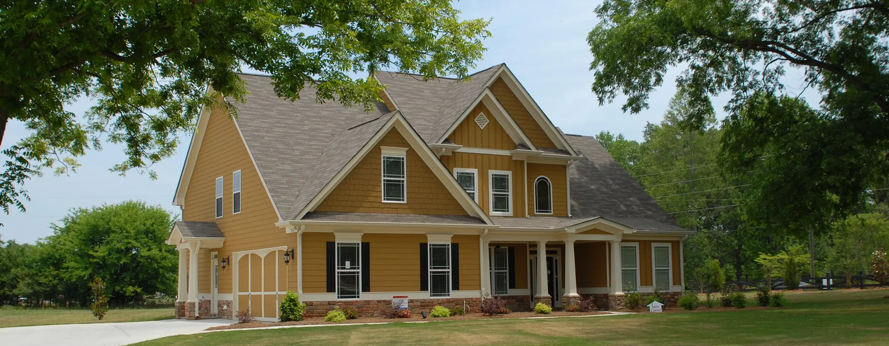 A large yellow house with a green lawn.