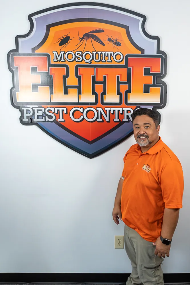 A man standing in front of a mosquito elite pest control sign.